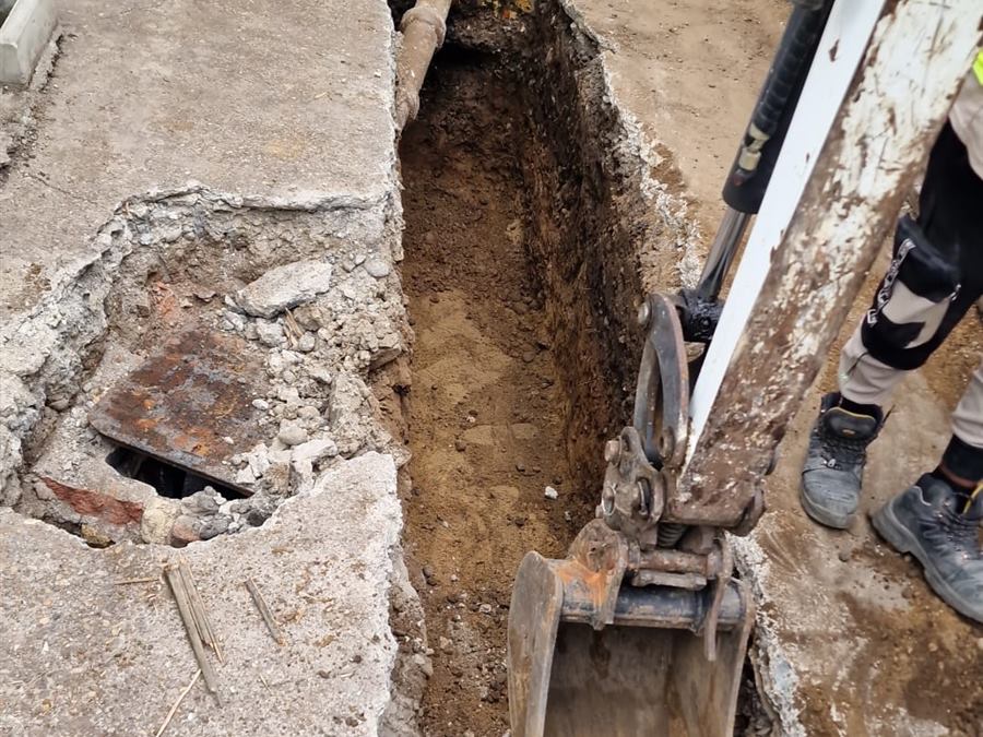 Excavator digging a foundation trench at the front of a house