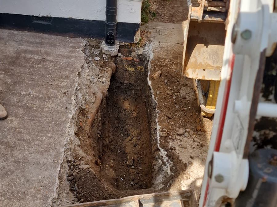 Mini digger excavating foundations beside a house